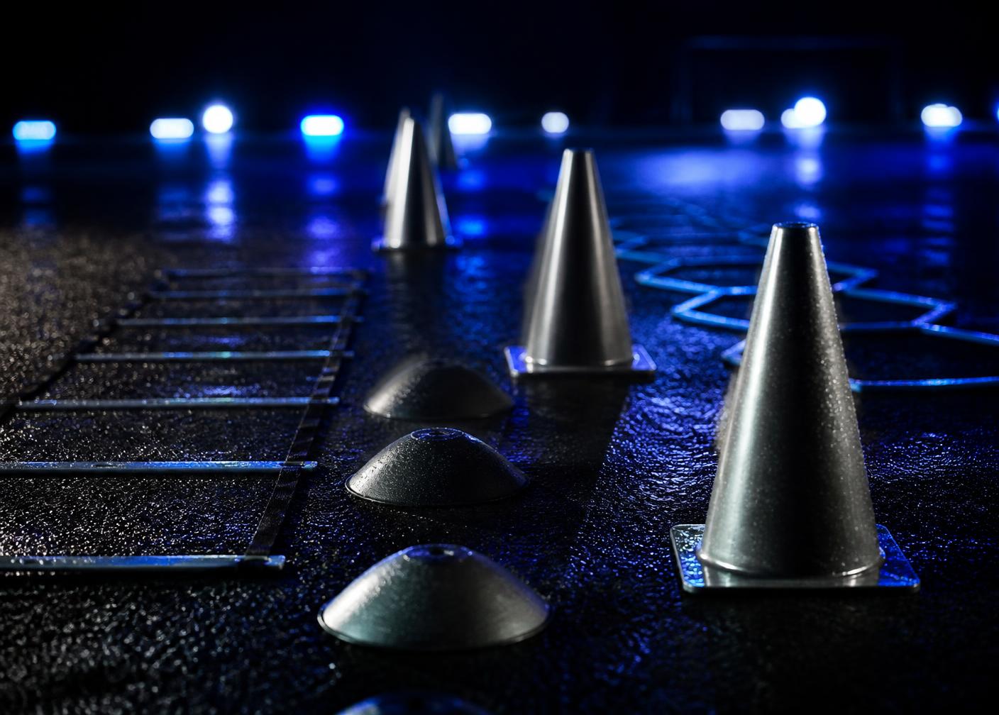 Training cones and agility equipment on a floodlit pitch at night